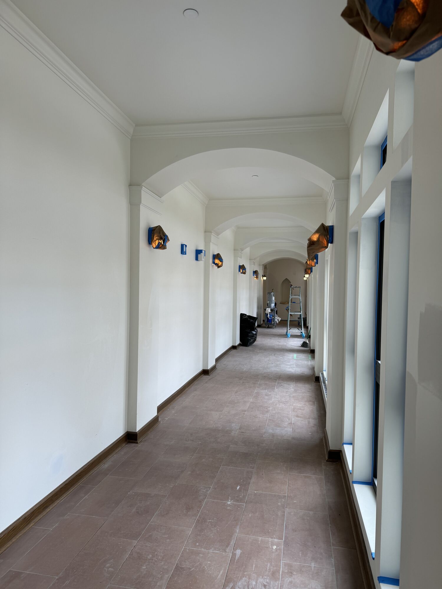 Arched corridor with crown molding and covered sconces